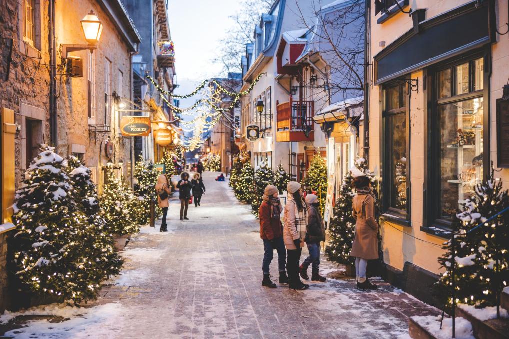 Rua do Petit-Champlain coberta de neve, com luzes festivas e montras iluminadas
